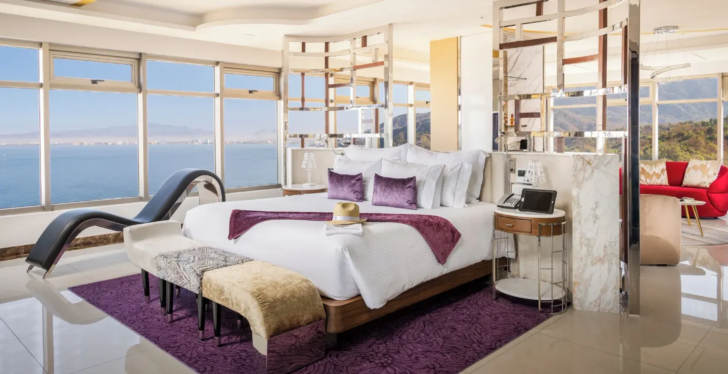 Master Suite king bed beside wide ocean-view windows at Hotel Mousai Puerto Vallarta.