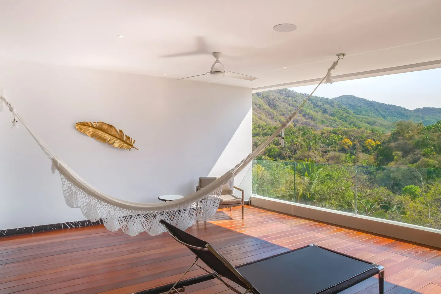 Suite terrace with hammock and green hillside view at Hotel Mousai Puerto Vallarta.