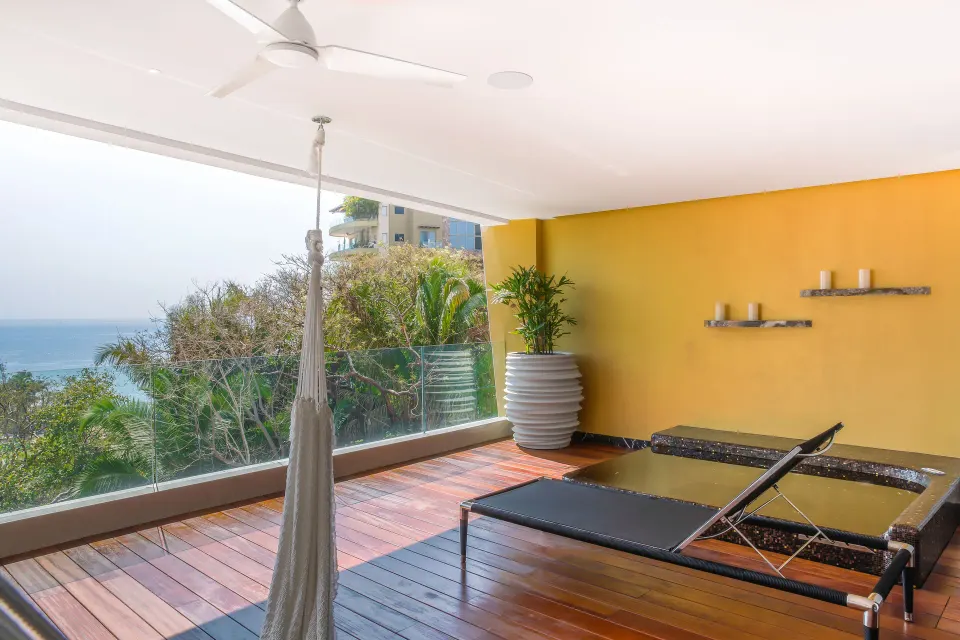 Suite terrace with hammock, loungers, and ocean glimpse at Hotel Mousai Puerto Vallarta.