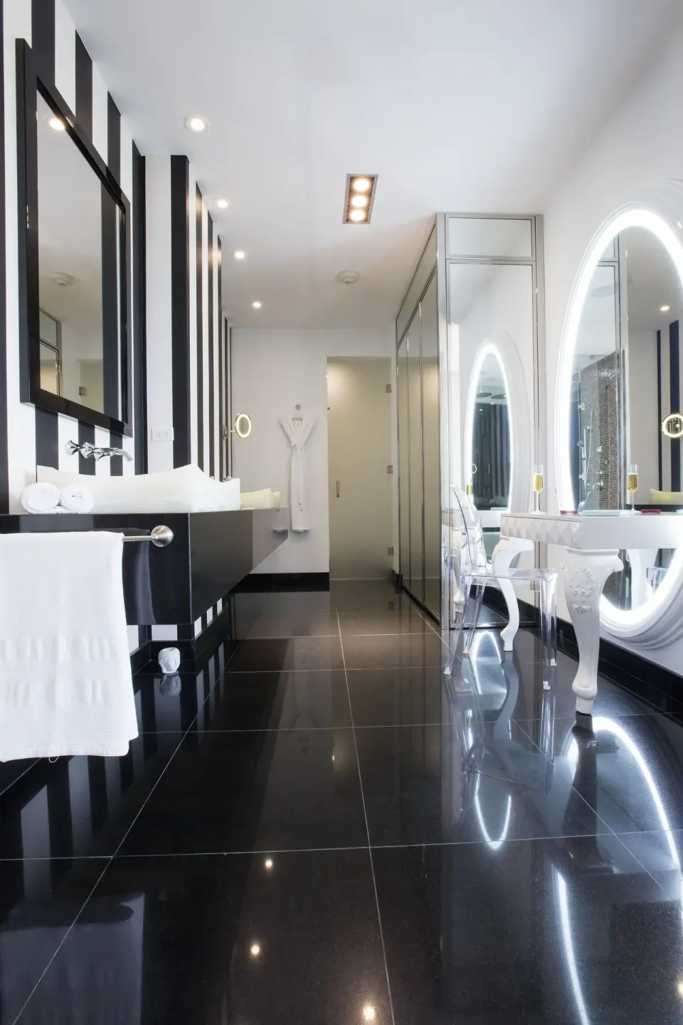 The Penthouse bathroom at Hotel Mousai Puerto Vallarta with glossy black floors and illuminated oval mirrors.