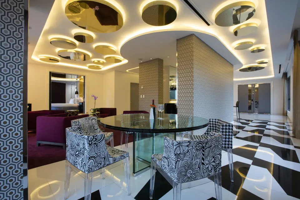 Glass dining table in The Penthouse at Hotel Mousai Puerto Vallarta beneath gold ceiling circles.