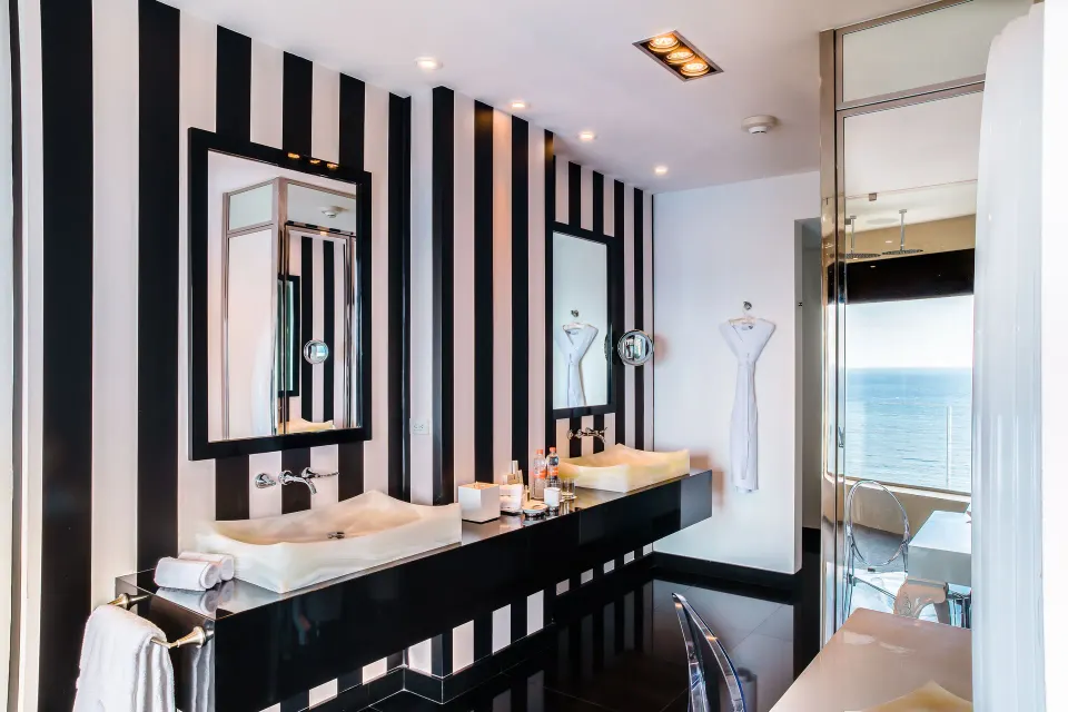 The Penthouse double vanity at Hotel Mousai Puerto Vallarta with striped walls and an ocean view beyond.