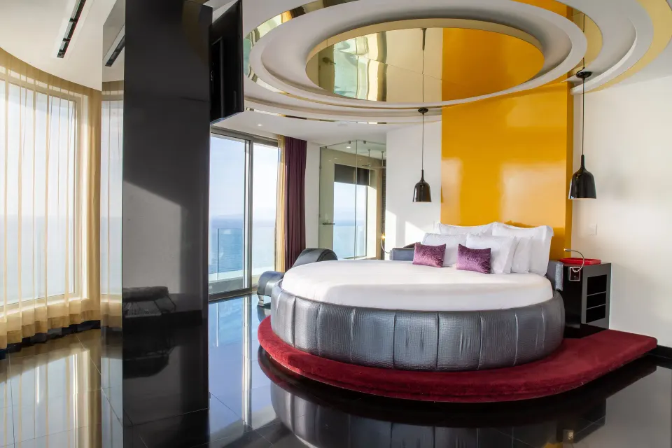 Round king bed in The Penthouse at Hotel Mousai Puerto Vallarta with ocean-facing glass doors.