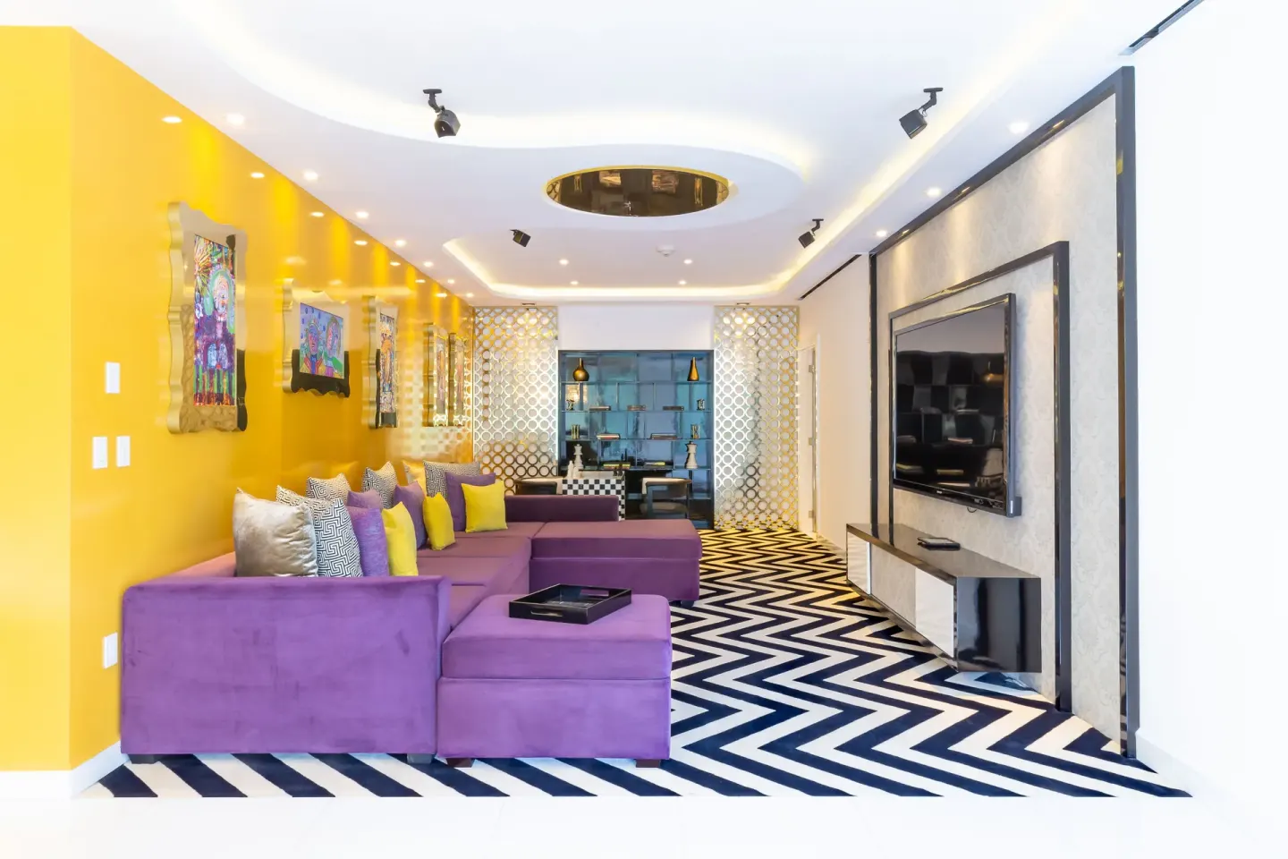 Purple sectional sofa in The Penthouse living room at Hotel Mousai Puerto Vallarta facing a wall-mounted TV.