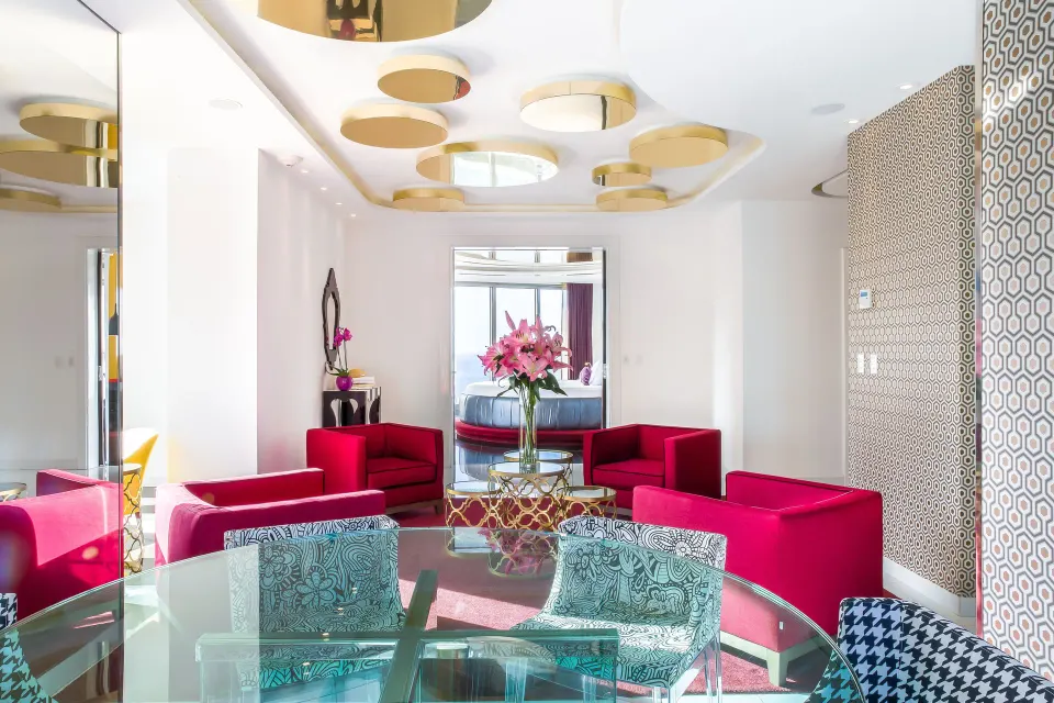 Sitting and dining space in The Penthouse at Hotel Mousai Puerto Vallarta with red chairs and flowers.