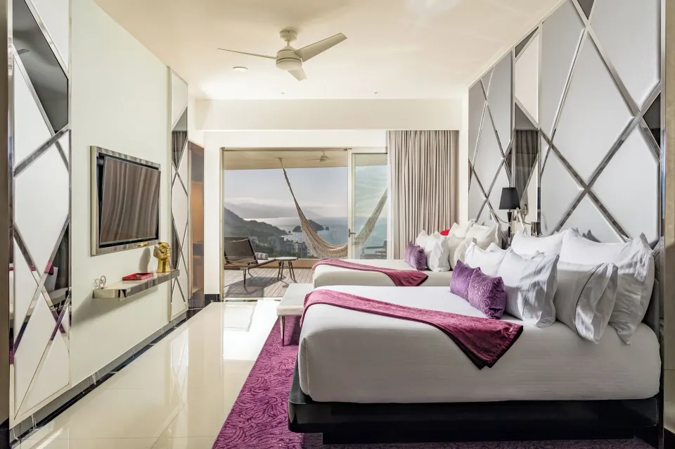 Ultra Two Bedroom Suite with two beds, TV, and balcony view at Hotel Mousai Puerto Vallarta.