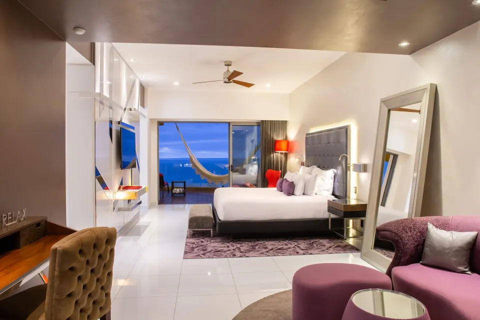 Ultra room with king bed, lounge area, balcony hammock, and ocean view at Hotel Mousai Puerto Vallarta.