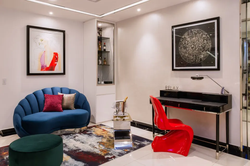 Ultra room sitting area with blue sofa, red chair, and writing desk at Hotel Mousai Puerto Vallarta.