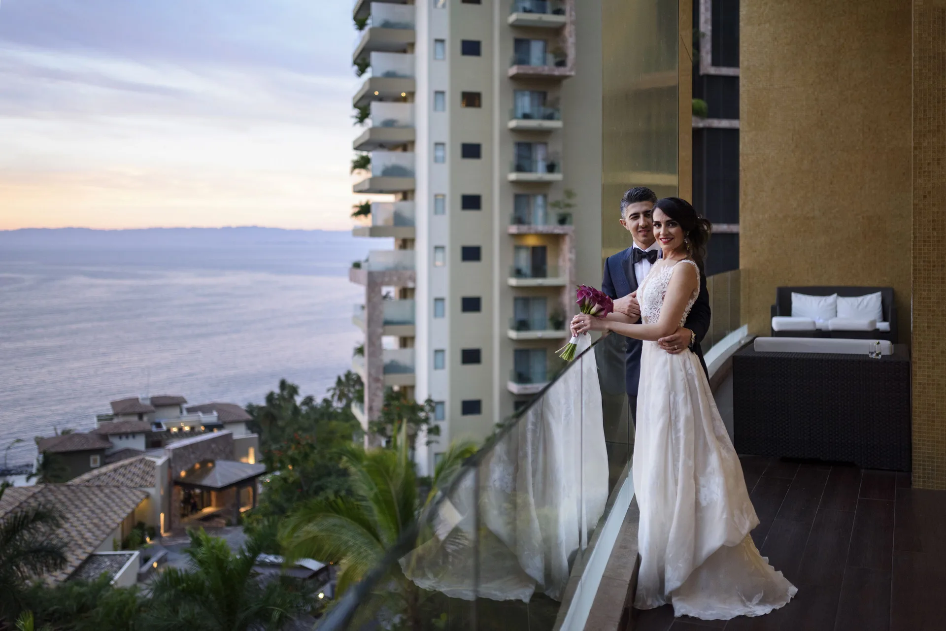 Bride and groom on a balcony overlooking the ocean at Hotel Mousai Puerto Vallarta.