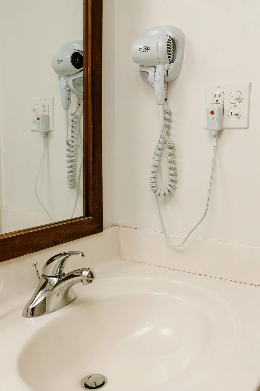 Bathroom sink with wall-mounted hair dryer and mirror at Hotel on the Cay.
