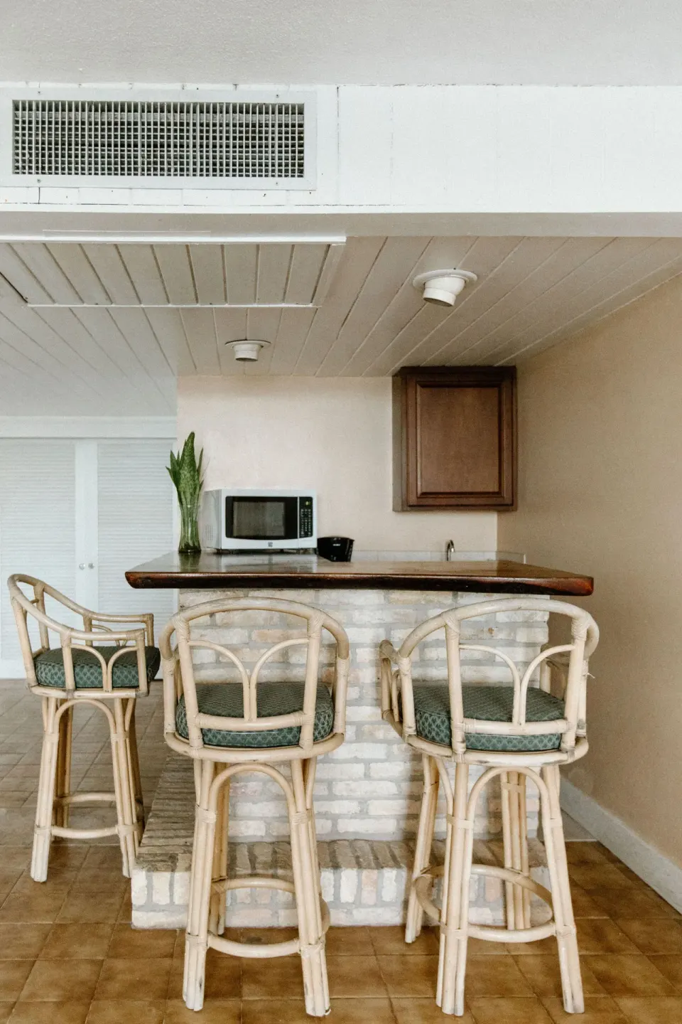 In-room bar counter with rattan stools and microwave at Hotel on the Cay.