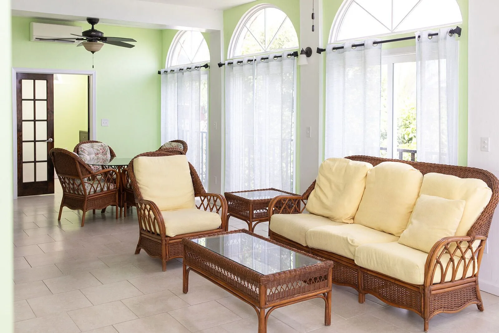 Living room with wicker seating, arched windows, and pale green walls at Hotel on the Cay.