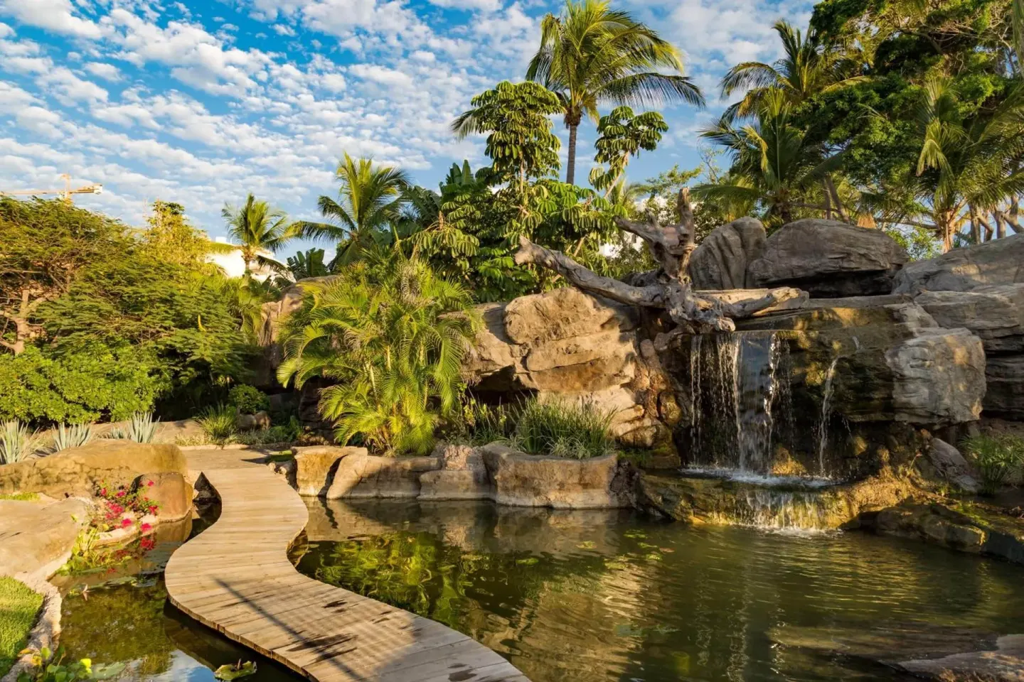 Rock waterfall, pond, and curved footbridge in the gardens at Hotel Playa Mazatlan.