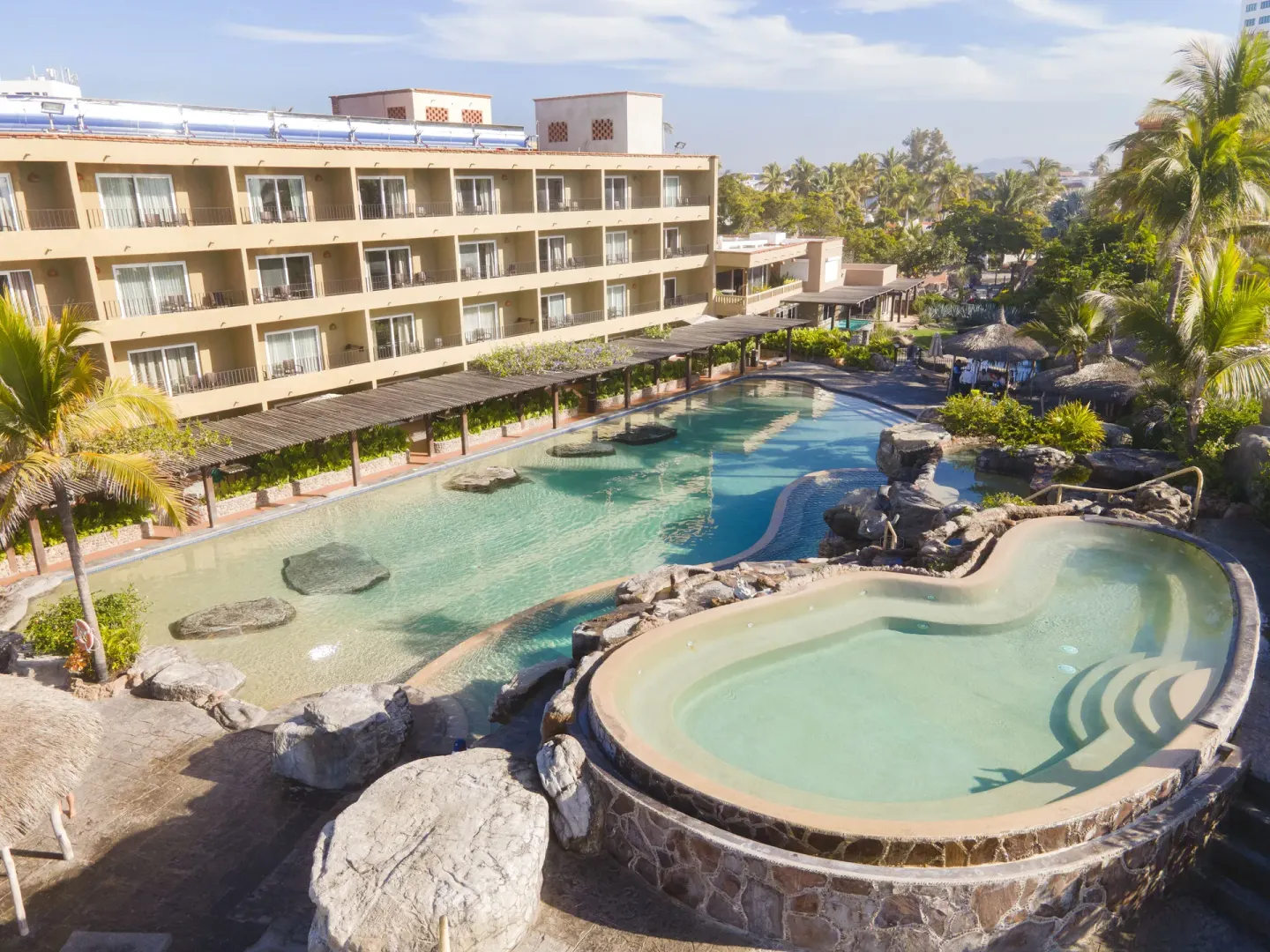 Large lagoon-style pool with rock landscaping and guestroom balconies at Hotel Playa Mazatlan.