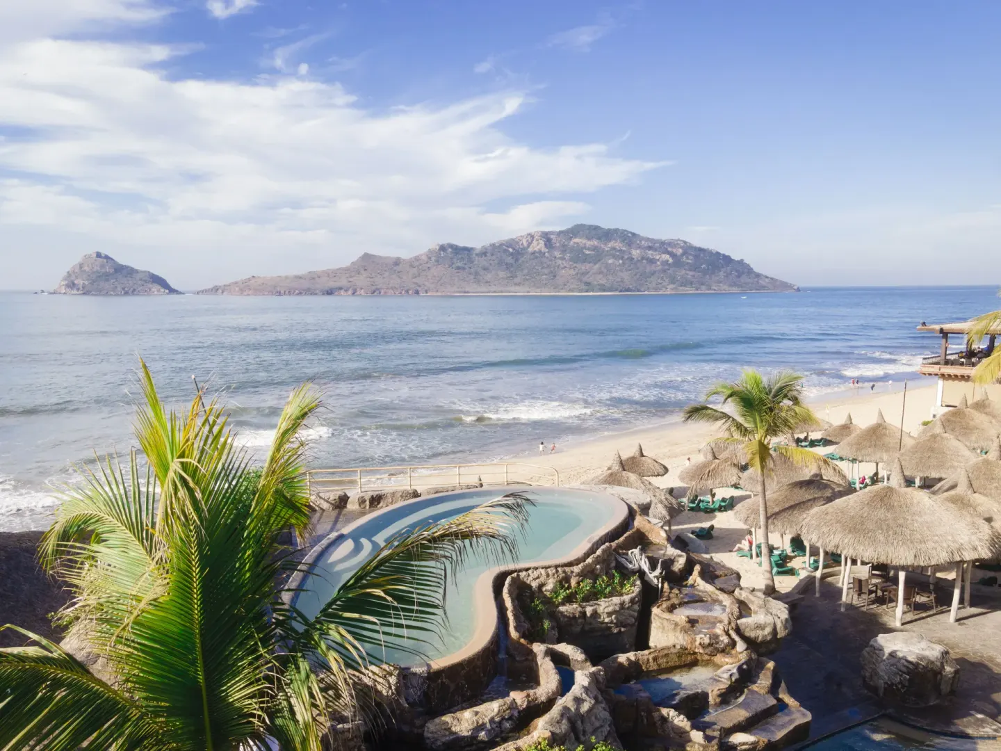 Oceanfront pool, palapas, and island view at Hotel Playa Mazatlan.