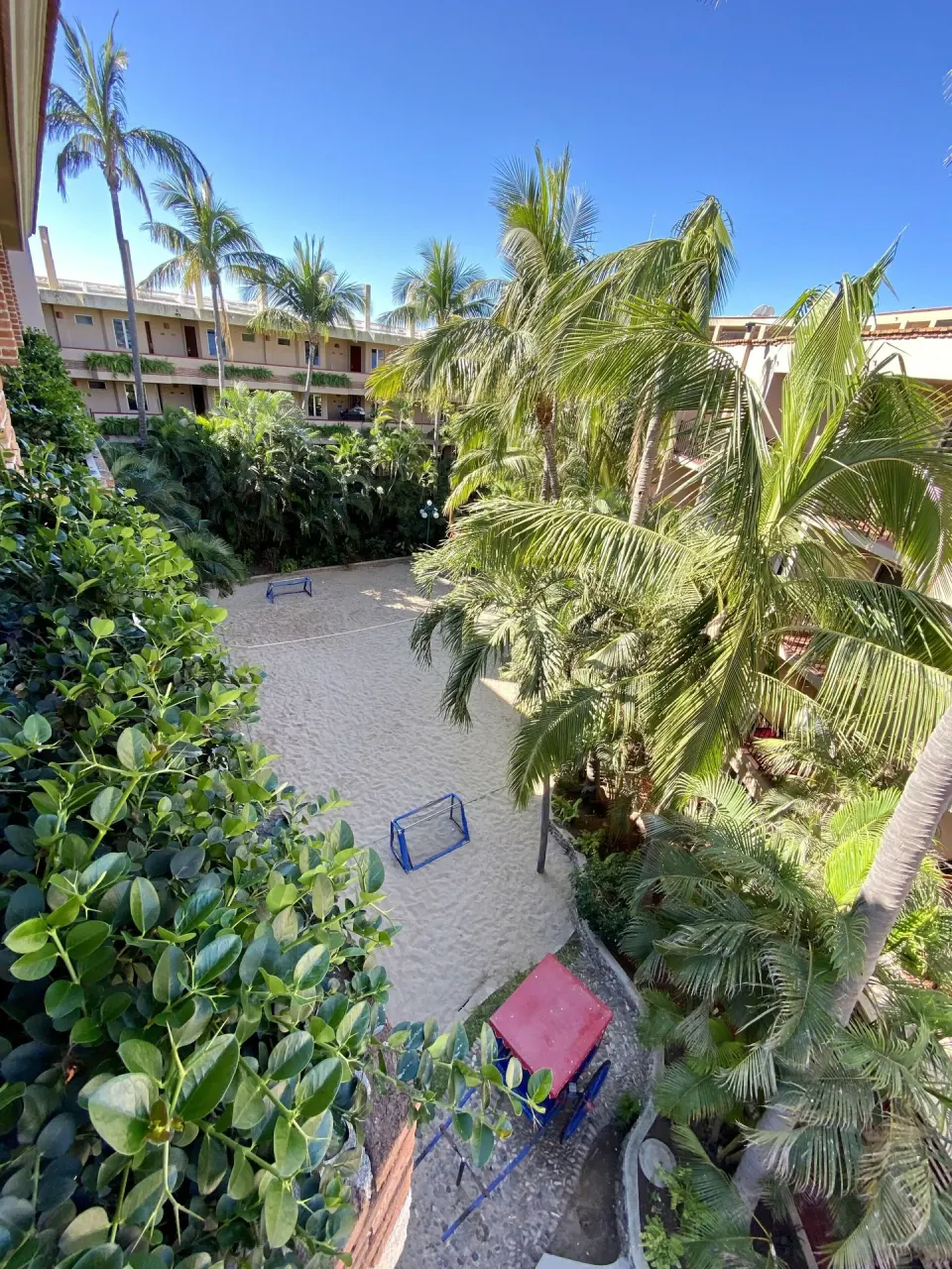 Palm-filled garden courtyard and sandy play area at Hotel Playa Mazatlan.