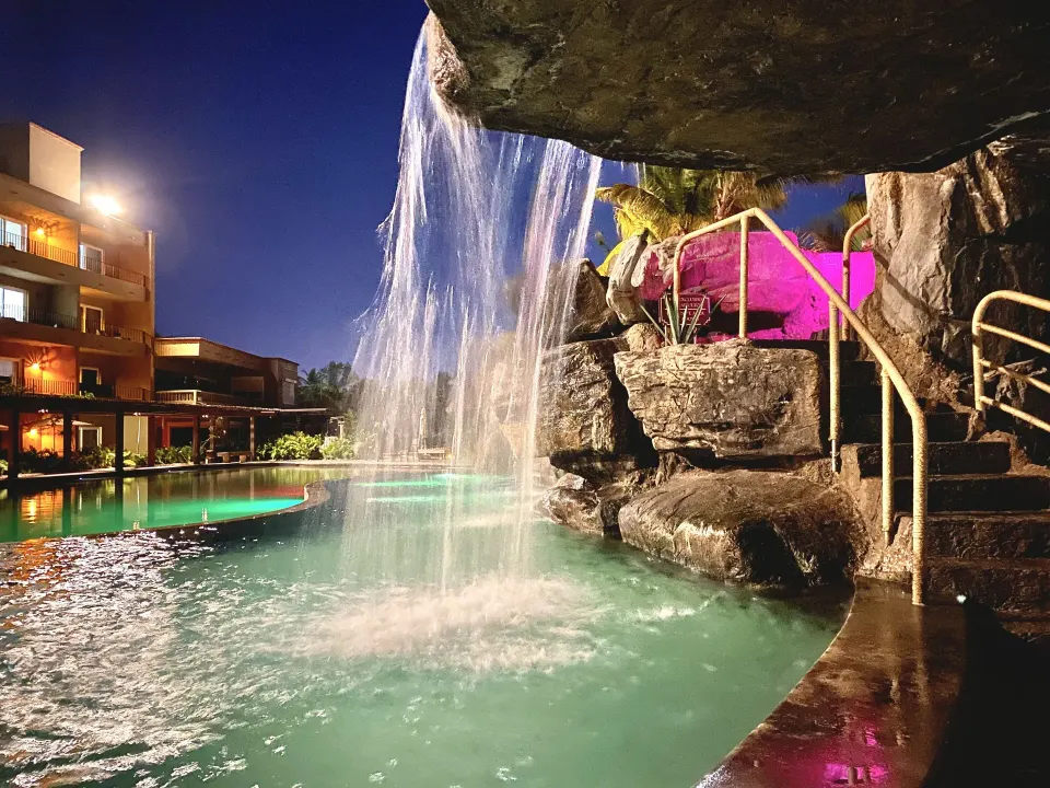 Nighttime rock waterfall pouring into a lit pool at Hotel Playa Mazatlan.