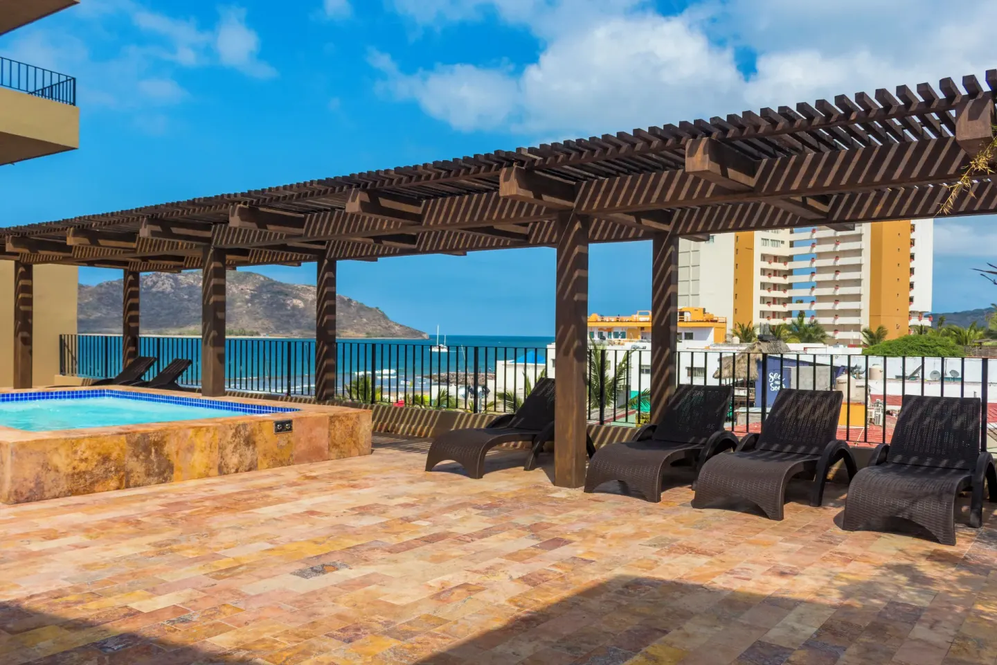 Rooftop pool deck with pergola loungers and ocean view at Hotel Playa Mazatlan.