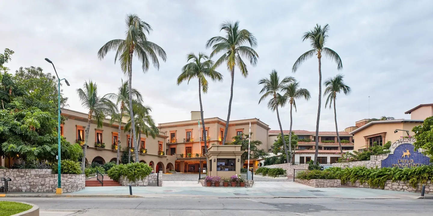 Street-front entrance with palms and arched buildings at Hotel Playa Mazatlan.