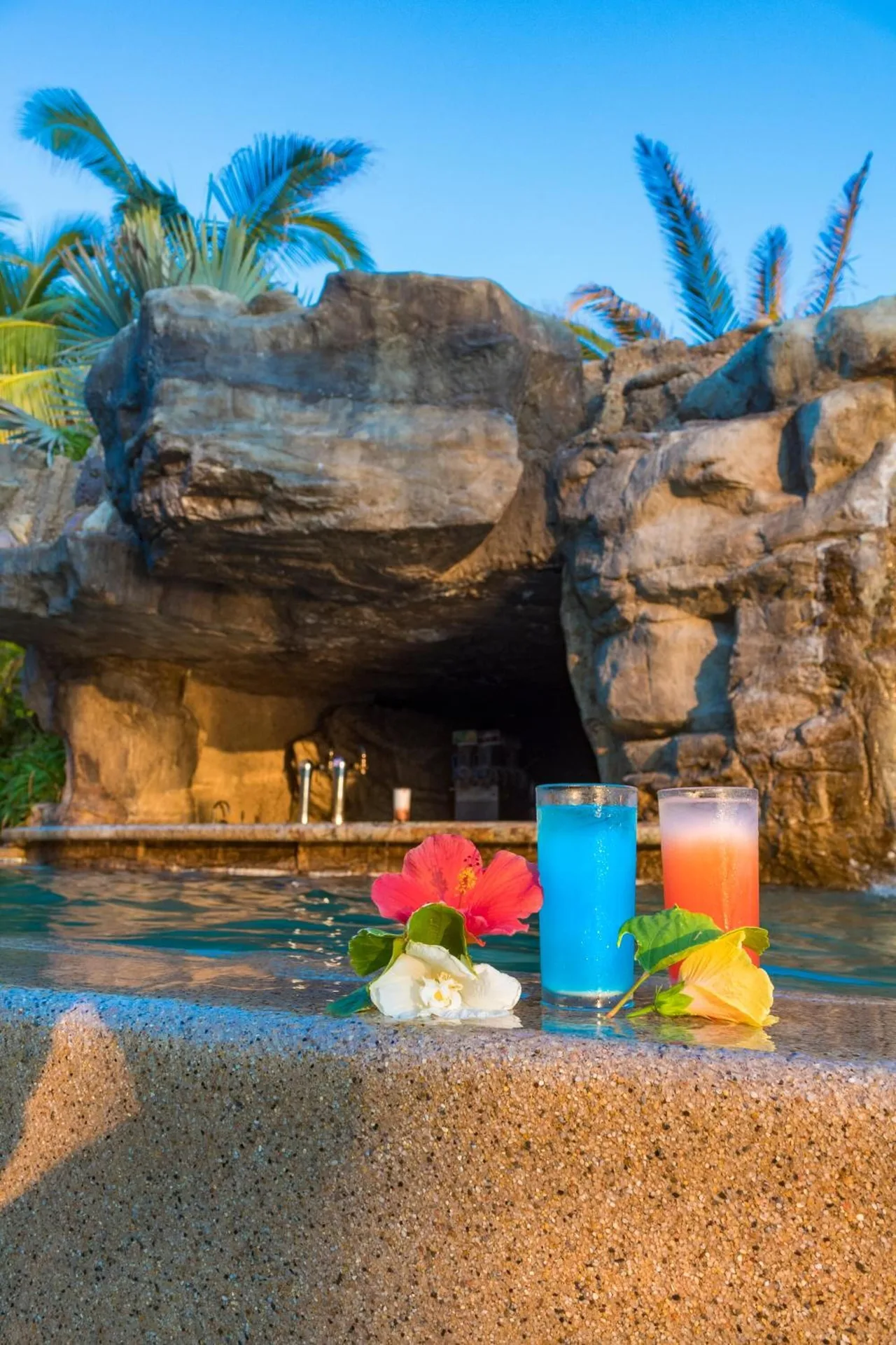 Colorful drinks on the swim-up bar ledge at Hotel Playa Mazatlan beside rockwork.