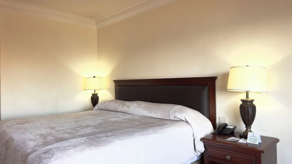 One-bed guest room with dark headboard and bedside lamps at Hotel Playa Mazatlan.