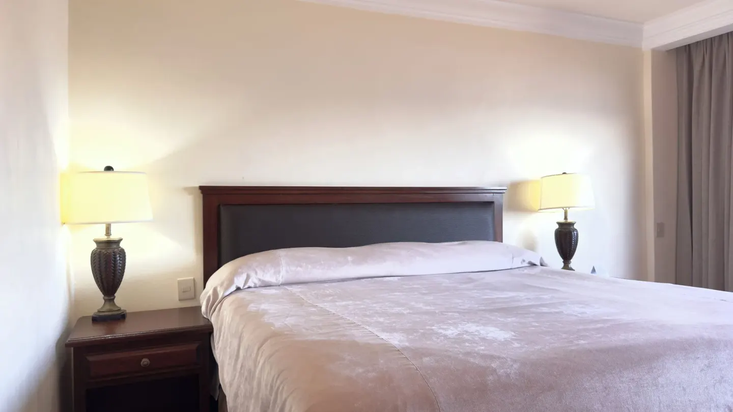 One-bed guest room with bedside lamps at Hotel Playa Mazatlan.