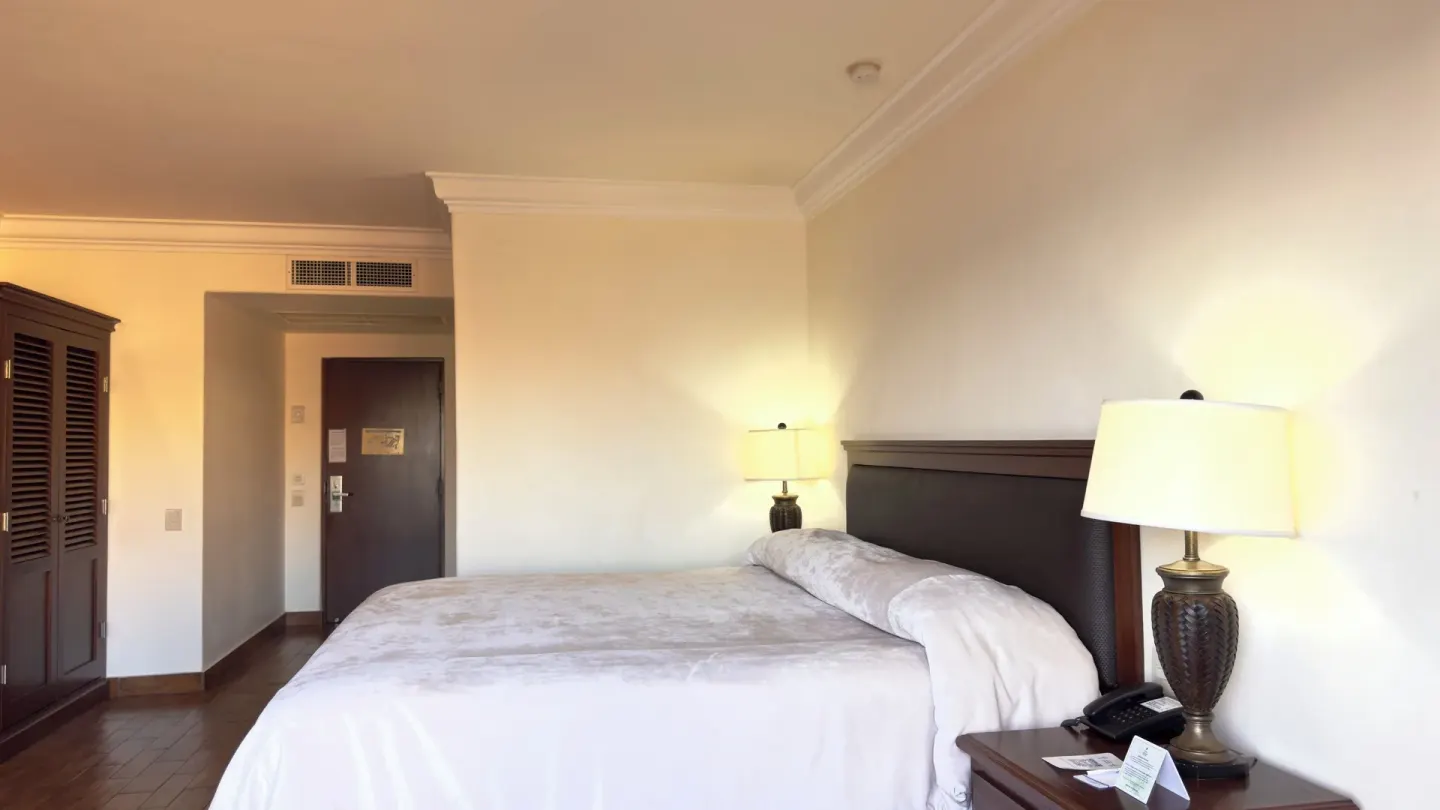 One-bed guest room with wardrobe, entry door, and bedside lamp at Hotel Playa Mazatlan.