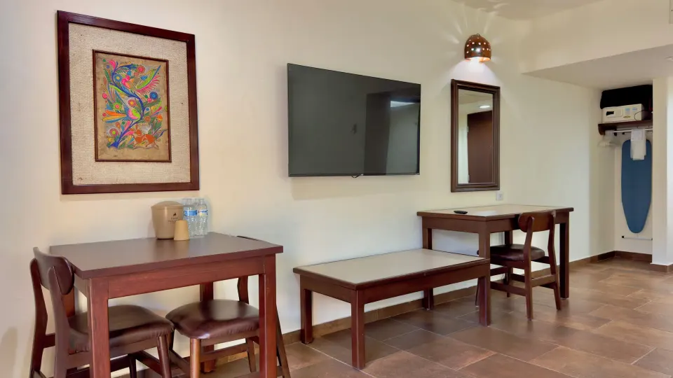 Standard room seating, TV, desk, and ironing area at Hotel Playa Mazatlan.