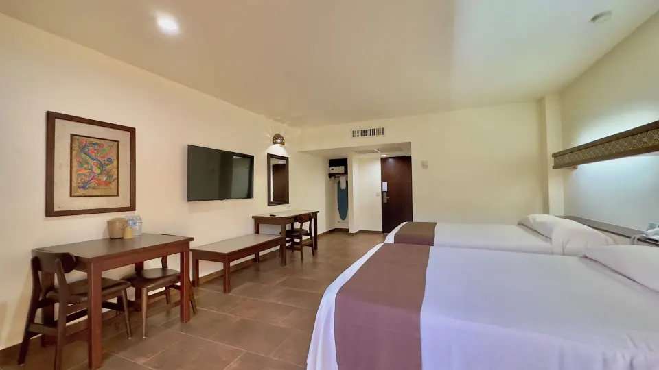 Standard room with two beds, dining table, desk, and TV at Hotel Playa Mazatlan.