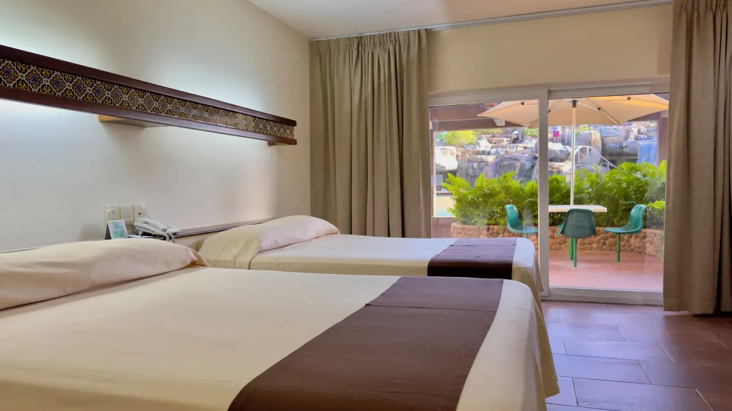 Standard room beds beside sliding patio door at Hotel Playa Mazatlan.