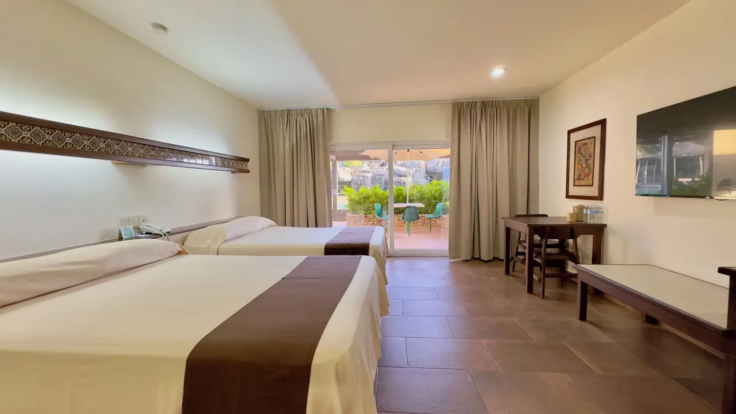 Standard room with two beds, TV, and patio view at Hotel Playa Mazatlan.