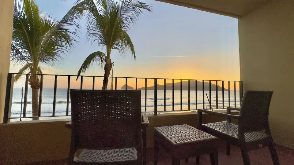 Oceanfront balcony with woven chairs at sunset at Hotel Playa Mazatlan.
