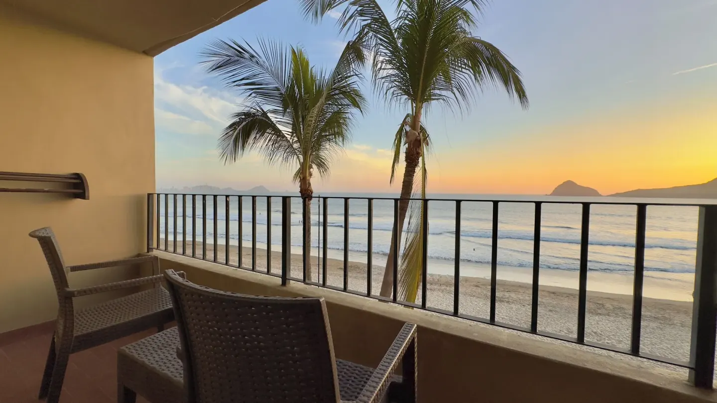 Balcony seating overlooking beach and palms at Hotel Playa Mazatlan.