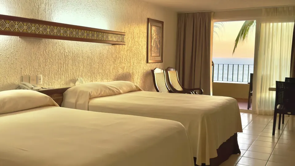 Two-bed ocean view room with chairs and balcony at Hotel Playa Mazatlan.