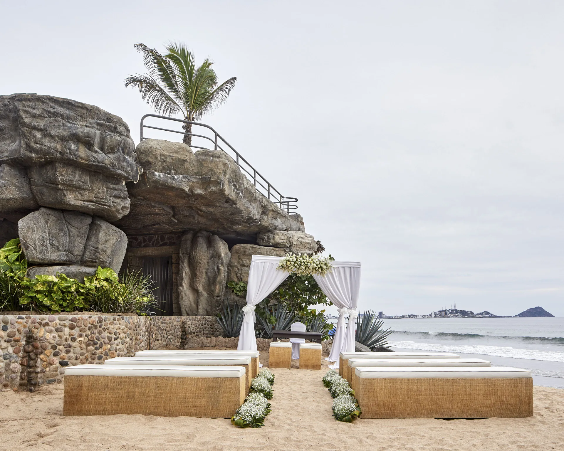 Beach wedding ceremony setup beside a rocky feature at Hotel Playa Mazatlan.