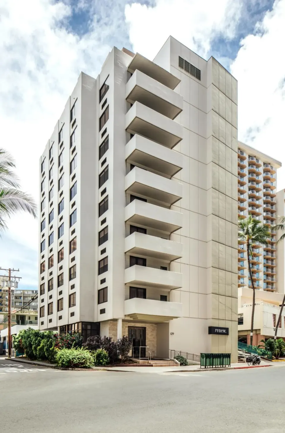Full exterior view of Hotel Renew showing balconies, windows, and corner entrance.