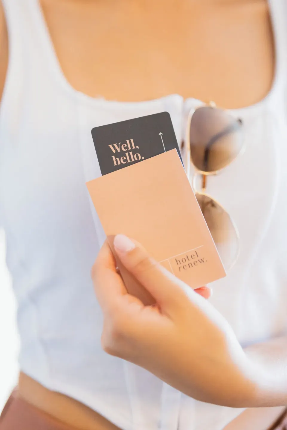 A guest holds a Hotel Renew key packet and card in bright light.