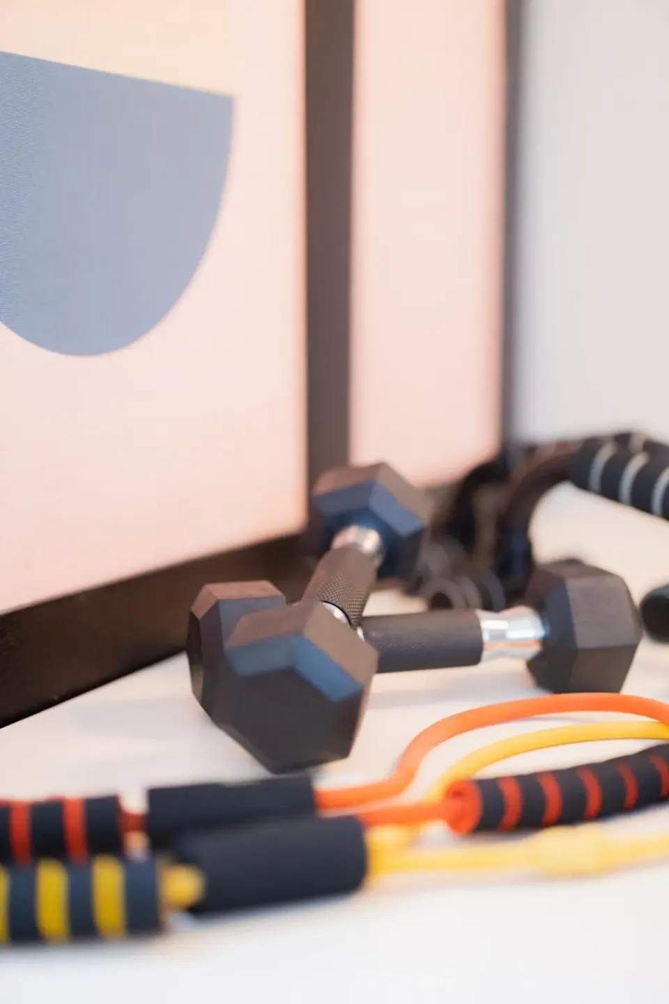 Dumbbells and resistance bands are arranged on a surface at Hotel Renew.