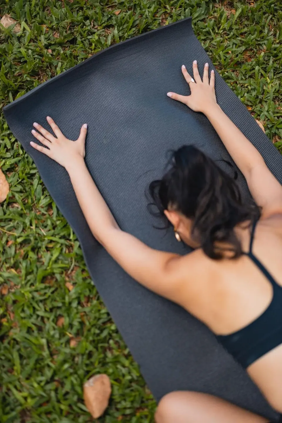 A guest stretches on a black mat on the grass at Hotel Renew.