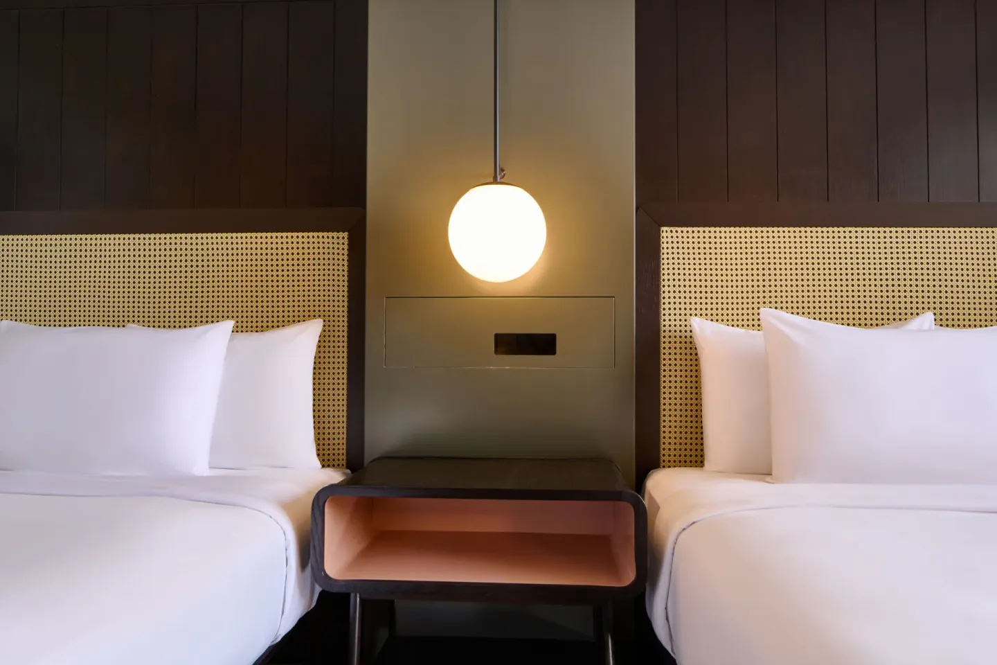 Two full beds with woven headboards and a glowing pendant light in a City View room at Hotel Renew.