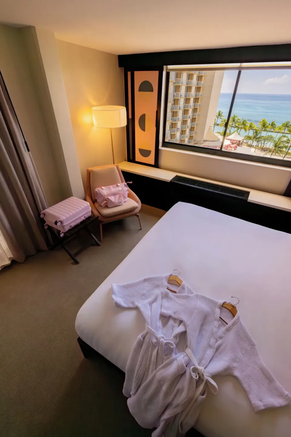 Corner Ocean View room with king bed, robes, chair, and ocean view at Hotel Renew.