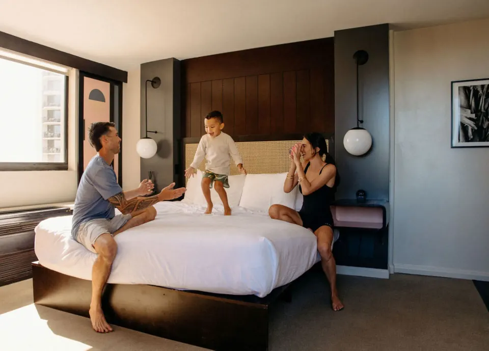 Family relaxing on a king bed in a Corner Room Ocean View with Balcony at Hotel Renew.