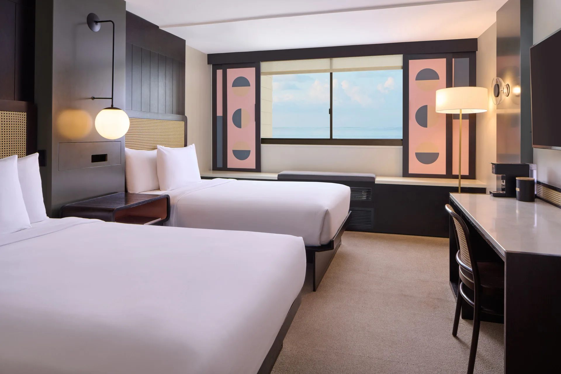 Ocean View 2 Full guest room with two beds, desk, and large window at Hotel Renew.
