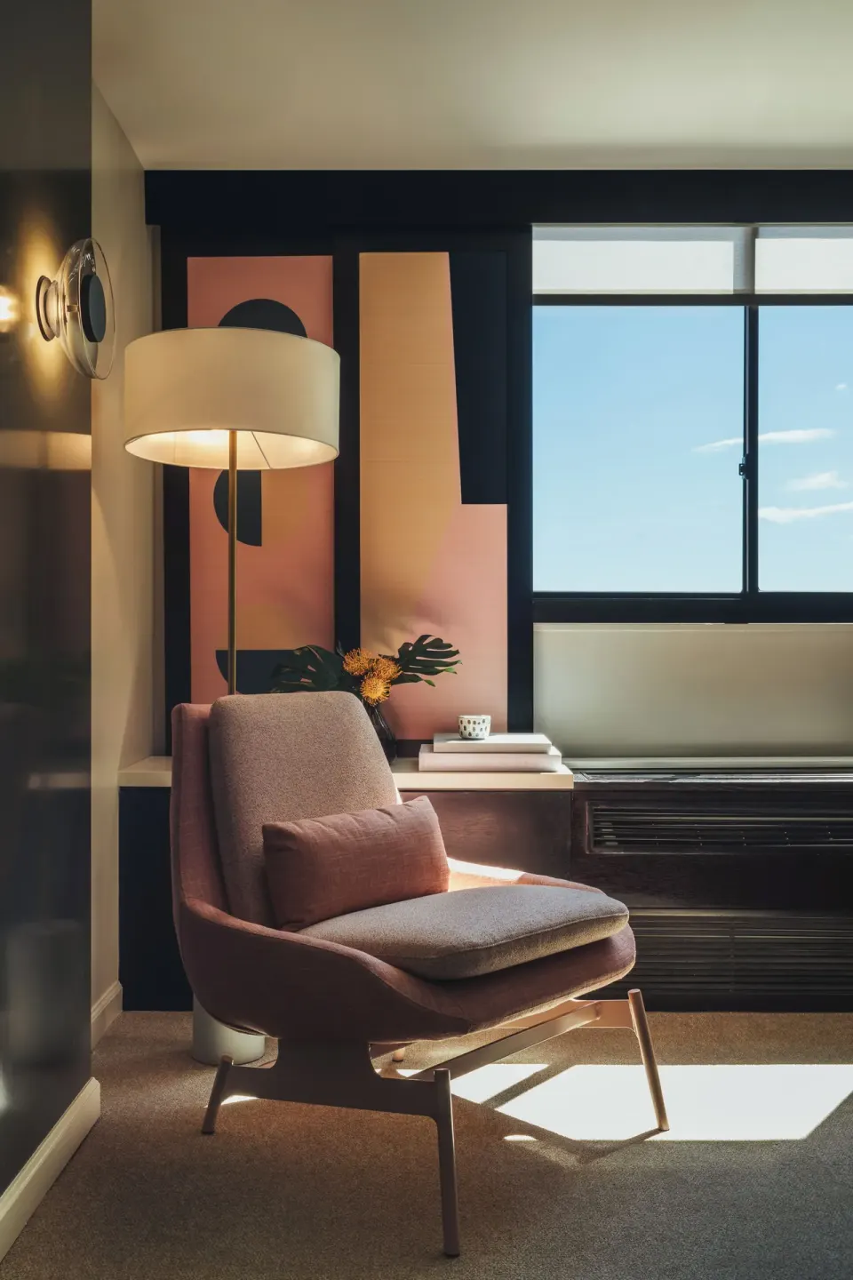 Sunlit Ocean View room corner with pink chair, floor lamp, side table, and window at Hotel Renew.