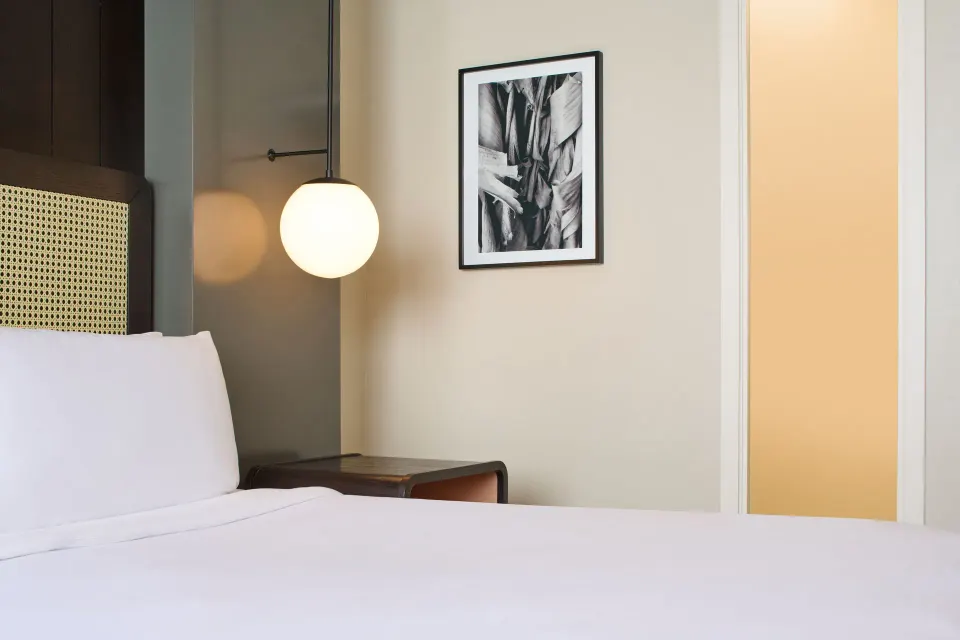 Standard Full room bed detail with pendant globe light and framed art at Hotel Renew.