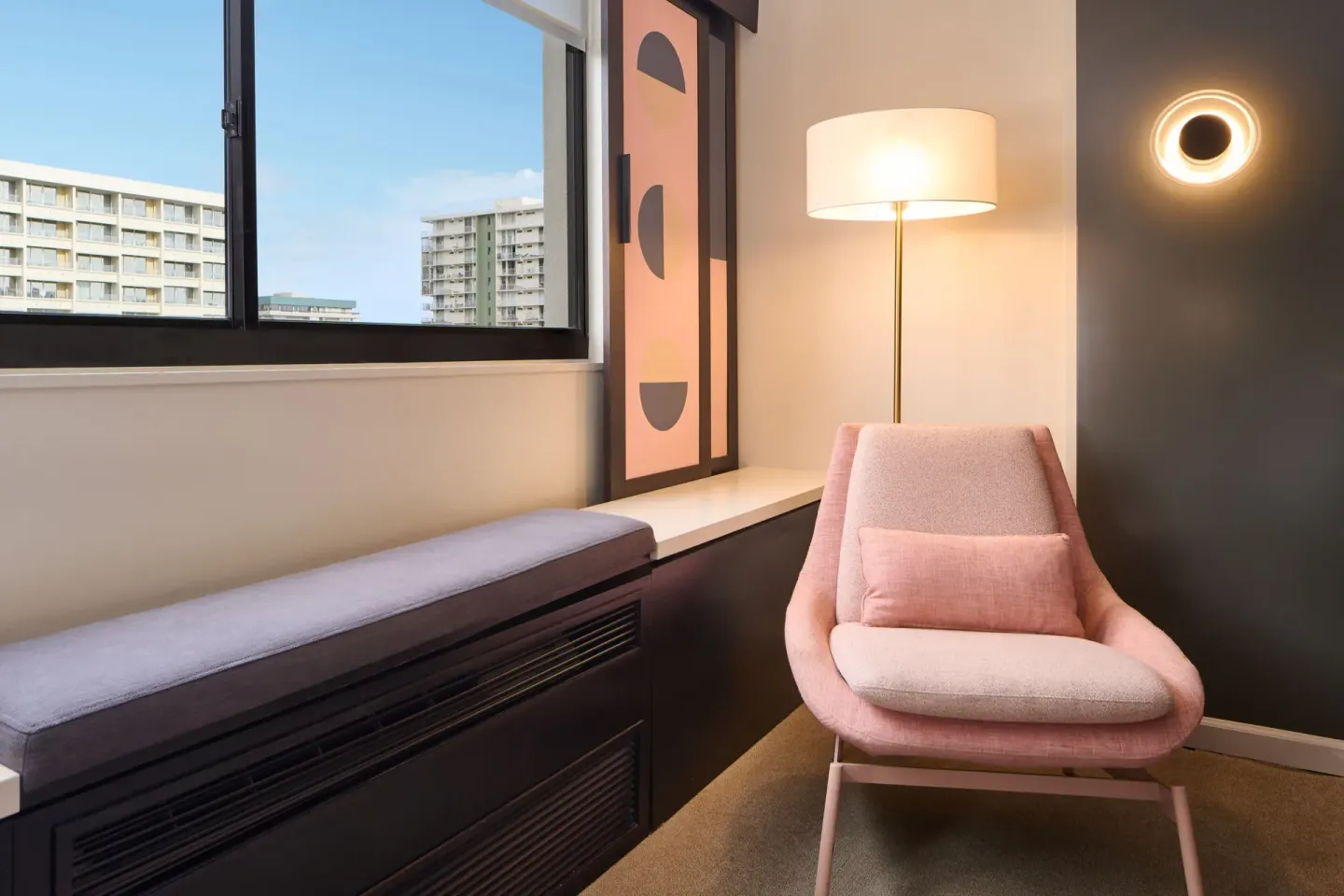 Standard Full room sitting nook with pink lounge chair and window bench at Hotel Renew.