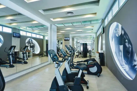 Fitness room with cardio machines and mirrors at Hotel Riu Bambu.