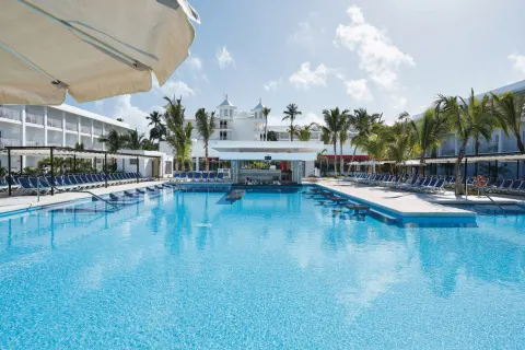 Large pool leading toward the swim-up bar and white buildings at Hotel Riu Bambu.