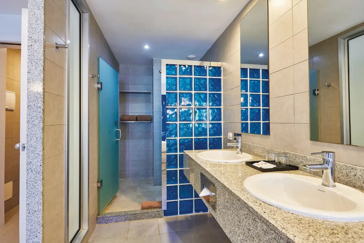 Deluxe Room bathroom with double sinks and glass-block shower at Hotel Riu Bambu.