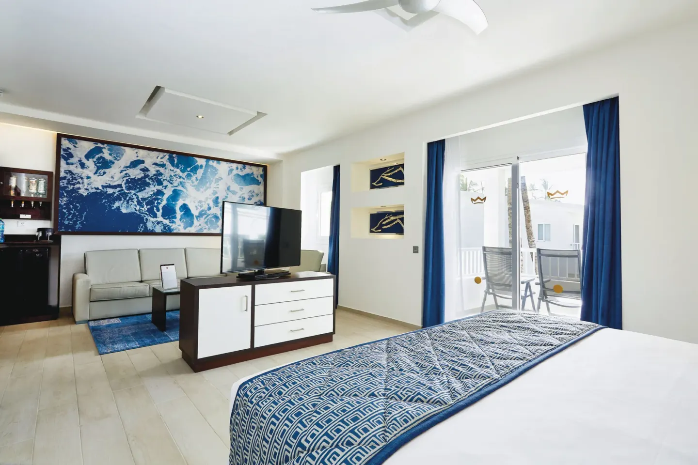 Junior Suite with bed, sofa, TV and balcony doors at Hotel Riu Bambu.